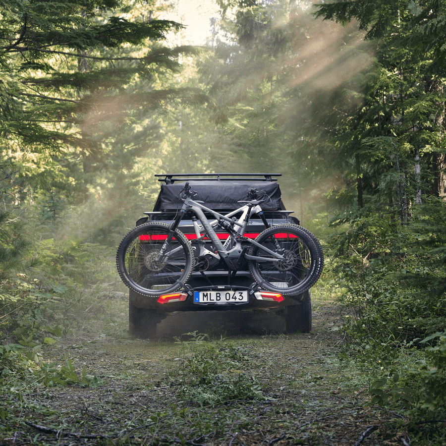 A car with a bike on a bike carrier is parked by a lake.