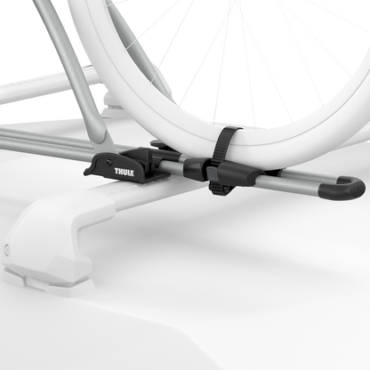 Close-up ghosted illustration showing the aluminum Thule FreeRide securing the bicycle wheels to the roof rack.